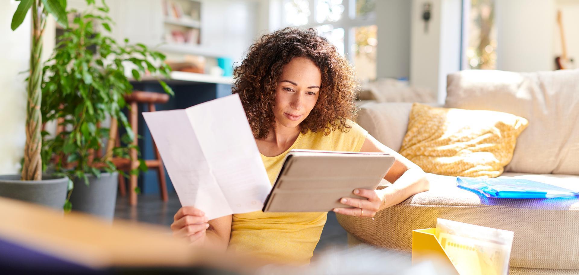 Confident woman sitting on the floor in her living room, reviewing job application materials in preparation for a job interview