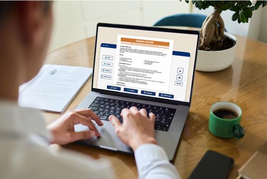 Person sitting at a desk using a laptop to write a targeted resume tailored to a specific job, with a cup of coffee and a printed resume on the desk